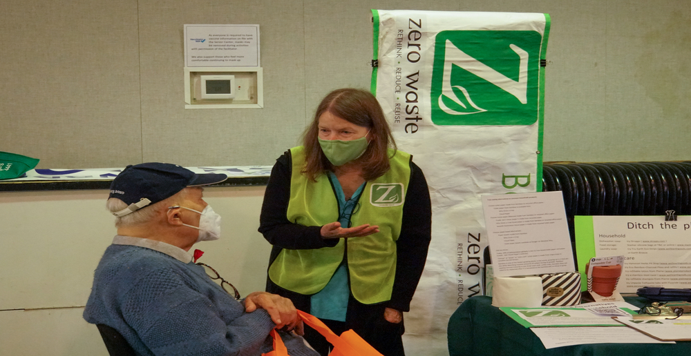 Volunteer speaking to a person at a fair booth.