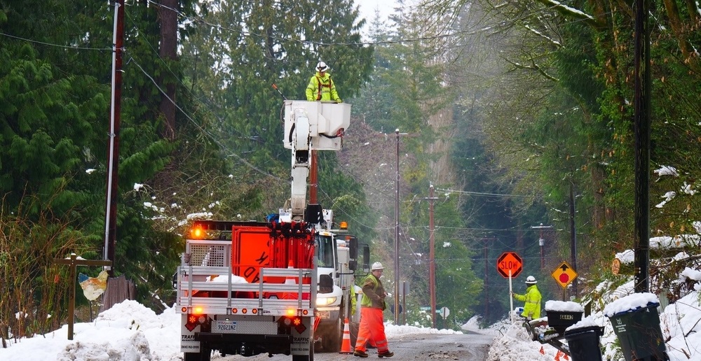PSE crews use a bucket truck to lift response workers up to a repair a power line during a snowstorm.